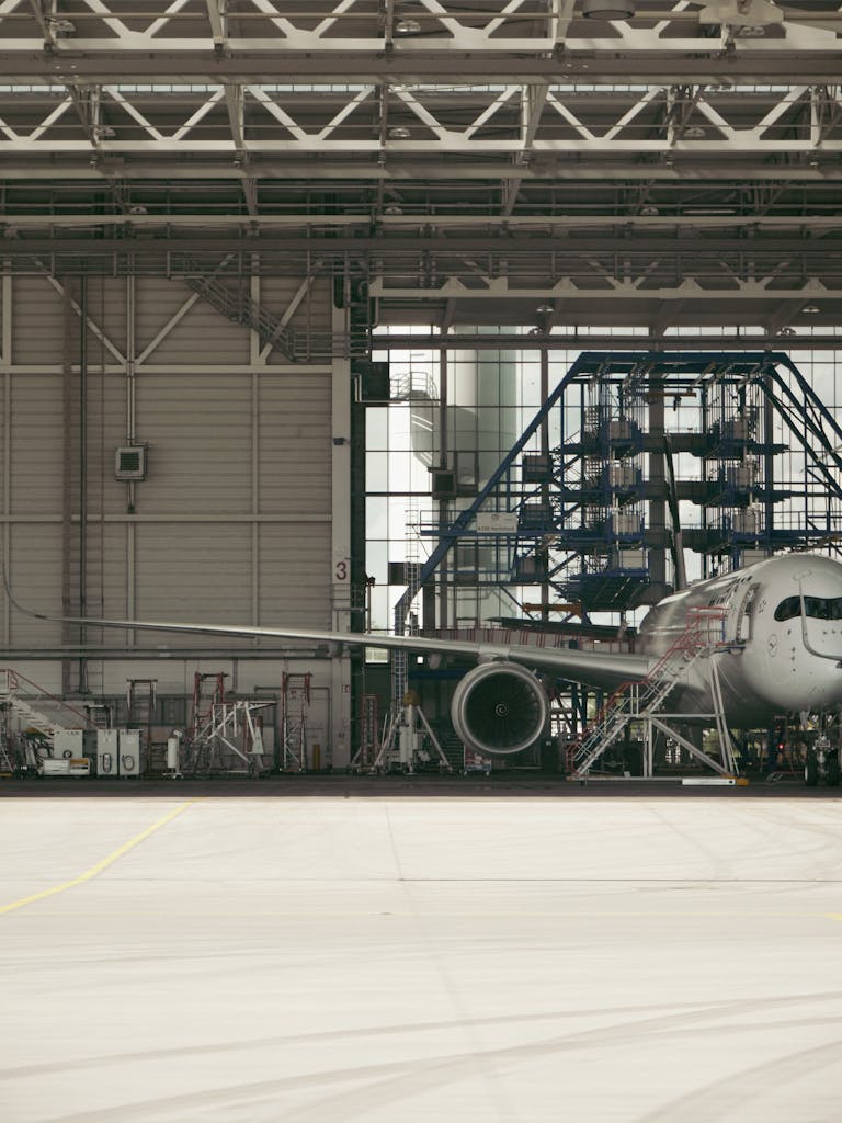 Detailed view of a commercial airplane undergoing maintenance inside an industrial hangar.